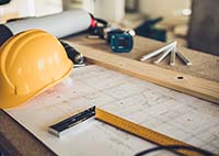 Image of architect table with tools, drawings, and a yellow hard hat