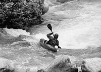 Black and white image of person white water kayaking