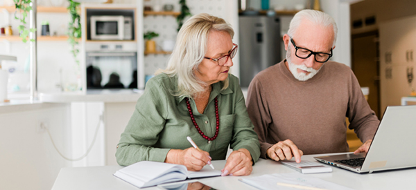 A mature couple looking over finances using a laptop computer at the table.