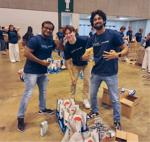 Three interns helping to pack food at a community event