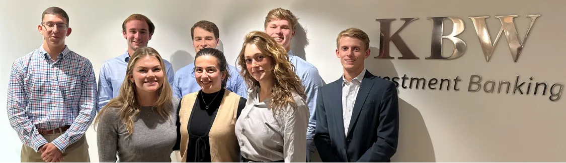 Group of interns in front of KBW logo in office