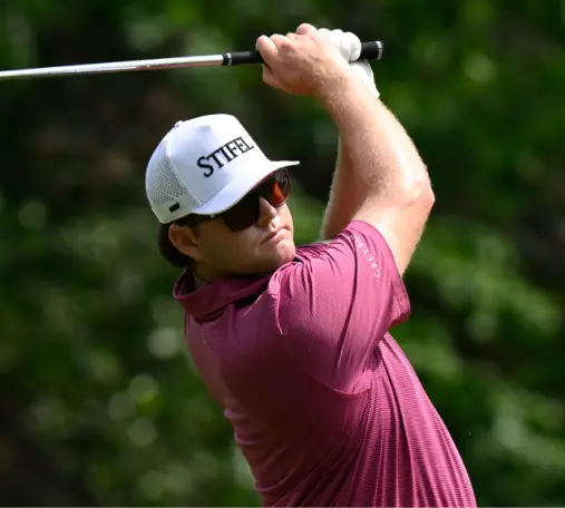 Professional golfer takes a swing while wearing a white Stifel branded hat