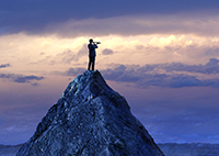 Image of person standing on mountain top looking out into distance with a monocular