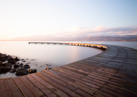 Image of dock going out into a large lake with mountains in the background